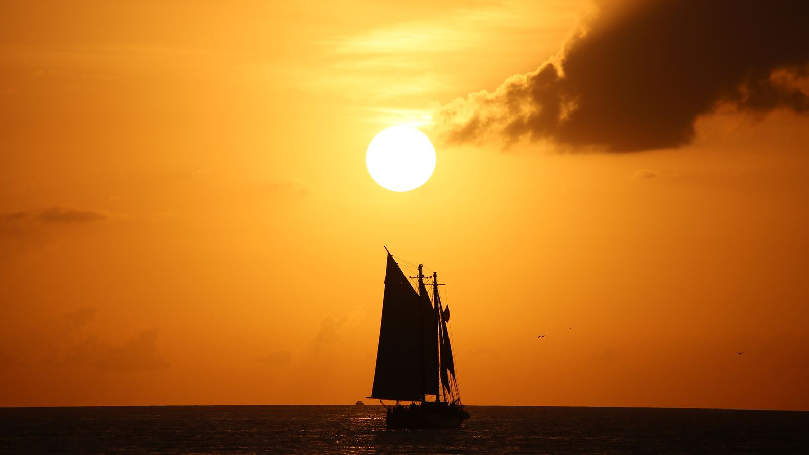 A schooner silhouetted against an orange sunset off Key West